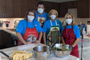 Four volunteers pose with a meal they made inside the Kathy's House kitchen